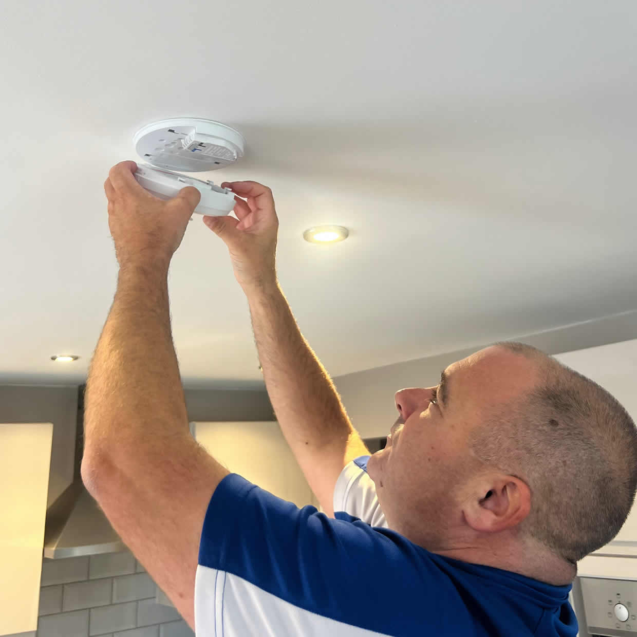 Smoke alarm installer fitting an alarm in a Hitchin property